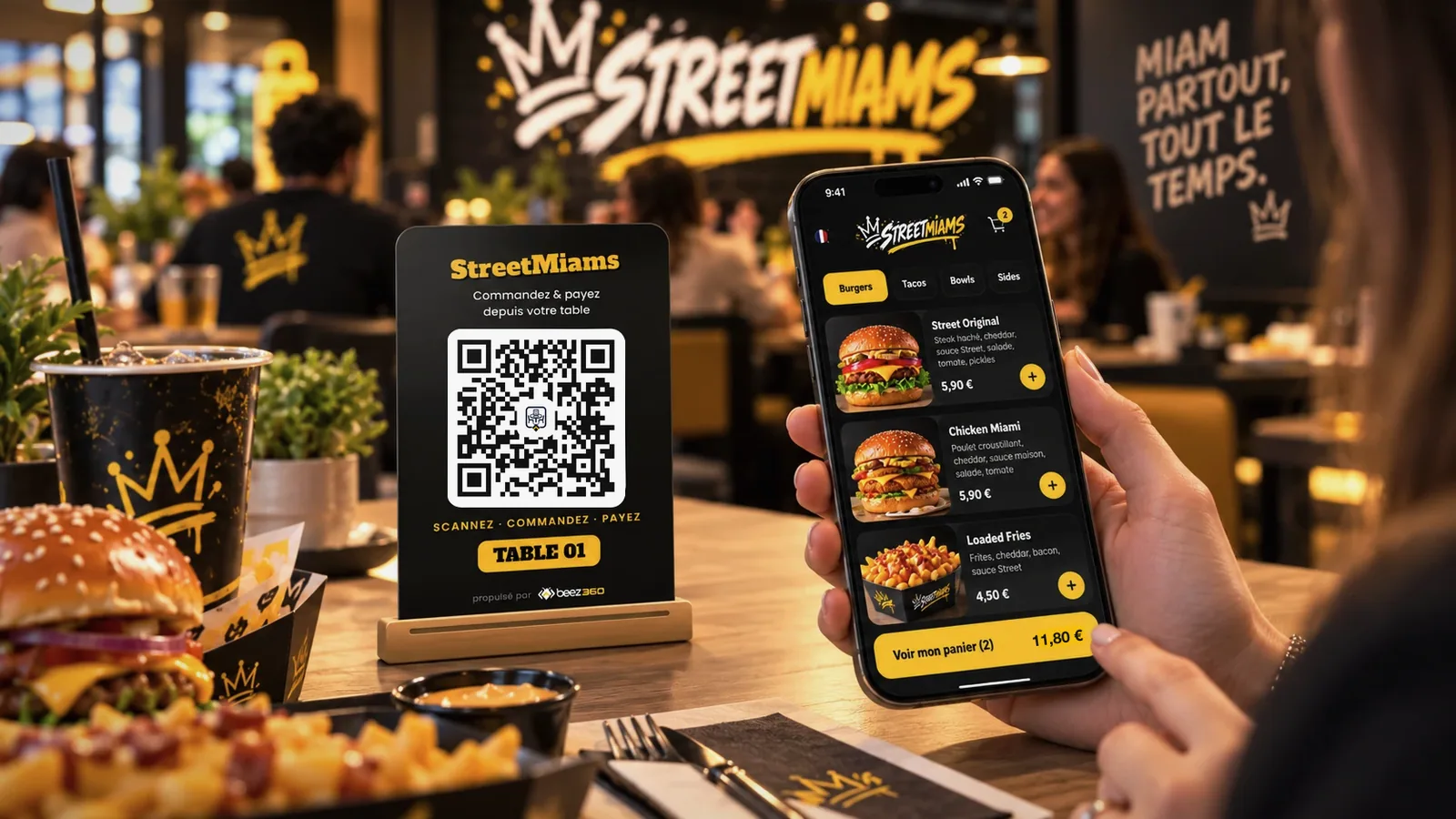 Cliente attablée dans un restaurant, téléphone en main affichant la carte en ligne, à côté d’un chevalet avec QR code et numéro de table.