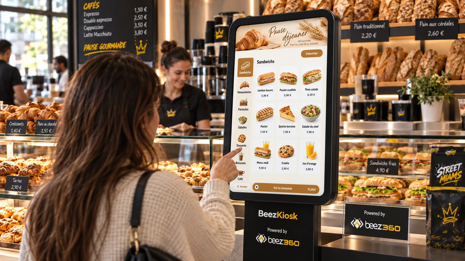 A customer uses a BeezKiosk terminal beside a bakery display, with Beez360 branding.